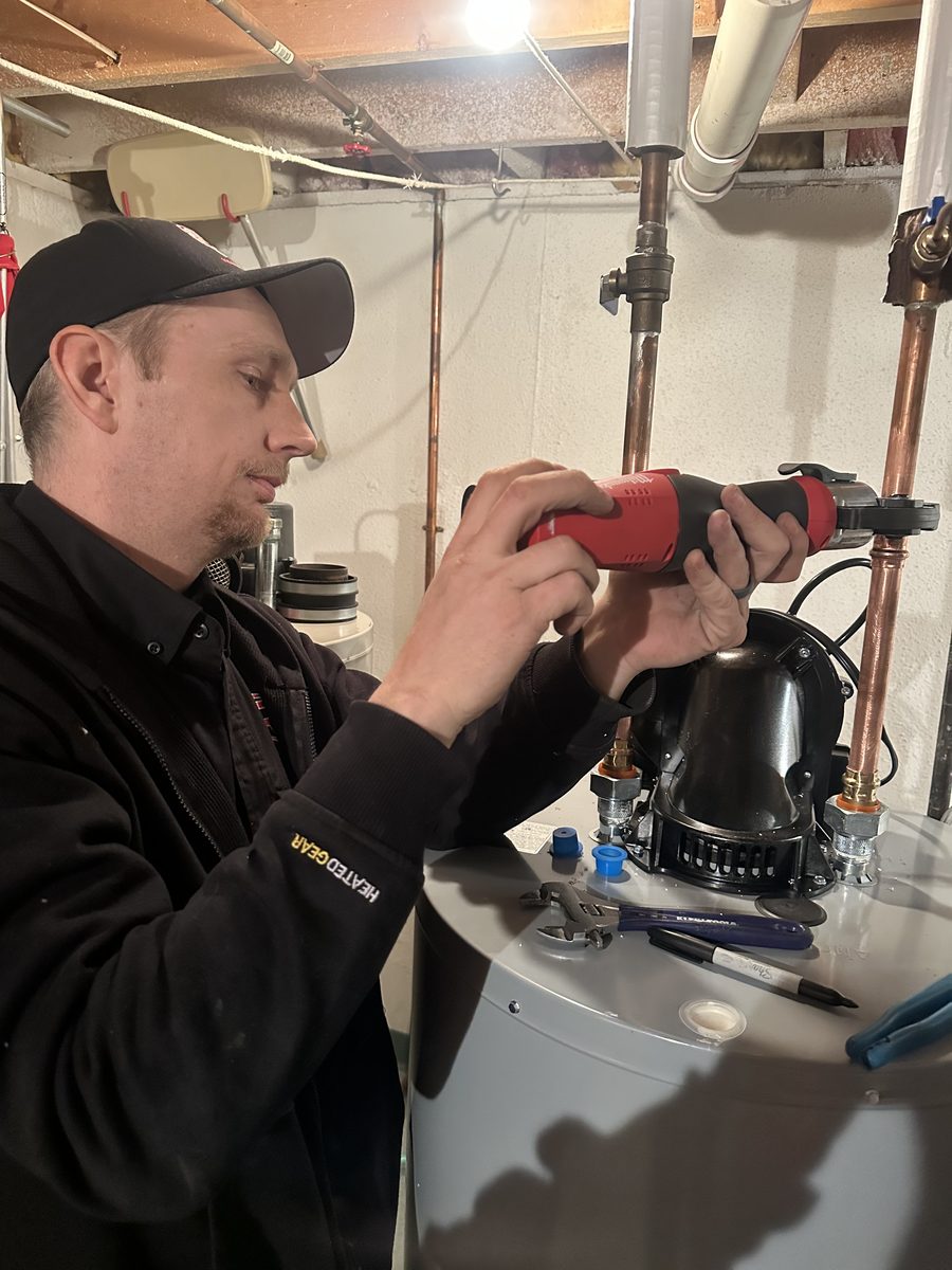 RC Heating & Cooling technician press-fitting a copper water line on a water heater